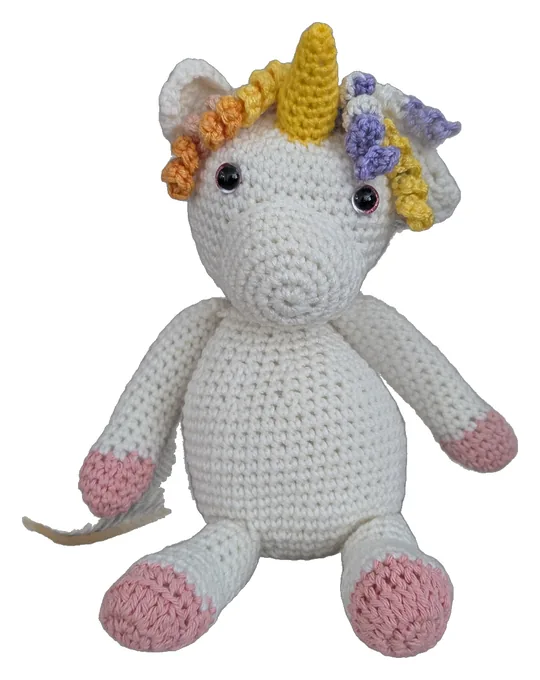 White crochet unicorn with a gold horn, a curly rainbow mane, and pink hooves